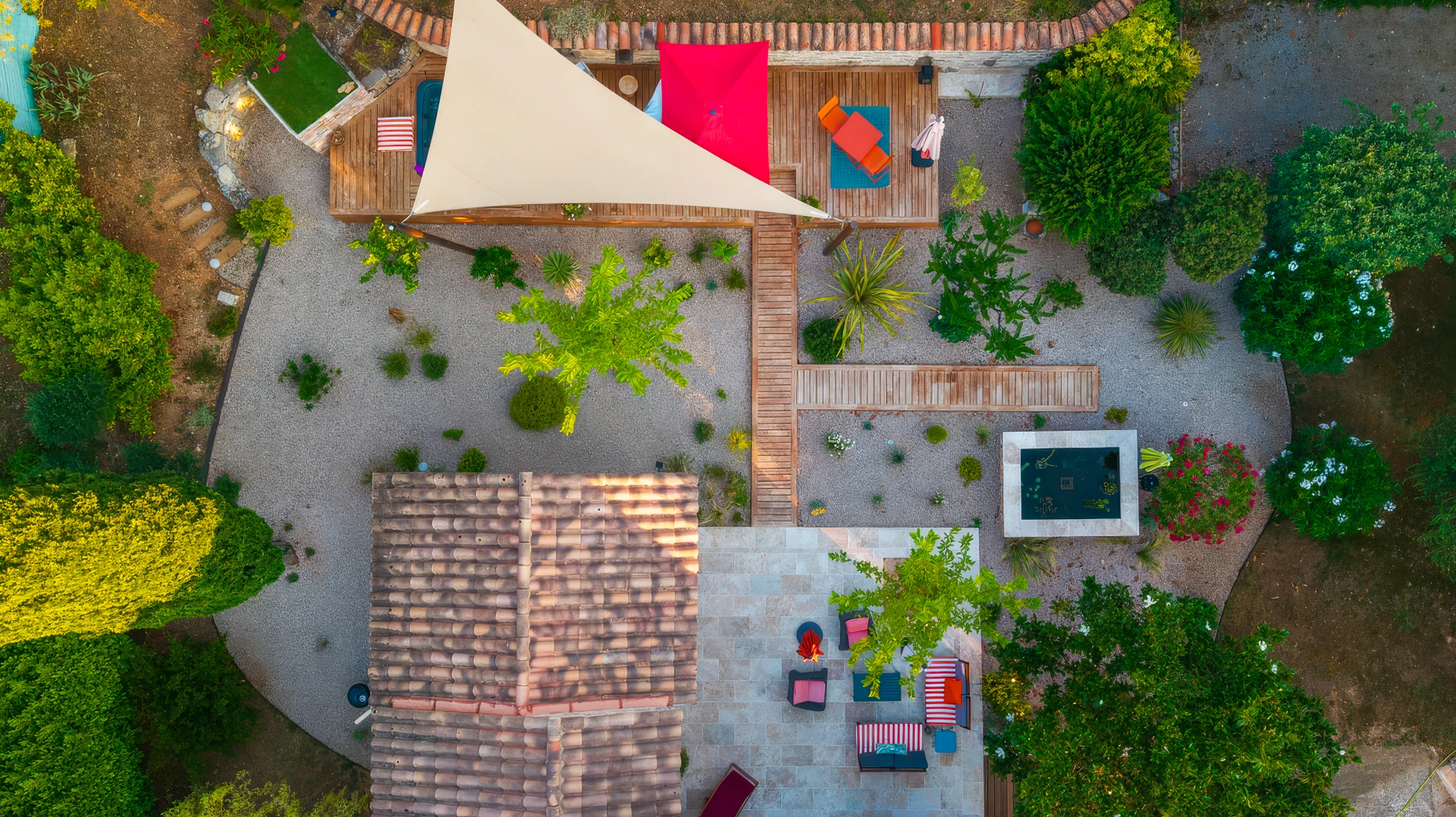 Terrasse extérieure moderne avec platelage bois, voile d'ombrage triangulaire beige tendu sur structure métallique